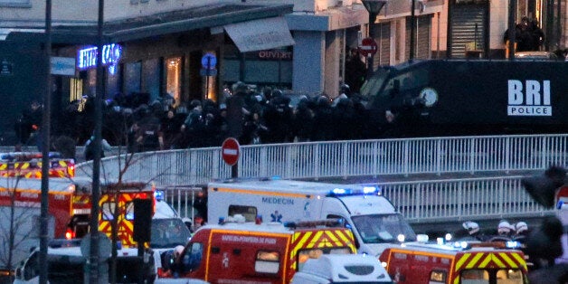 Police officers storm the kosher market where a gunman held several hostages, in Paris, Friday Jan. 9, 2015. The assault came moments after a similar raid on the building where two brothers suspected in the Charlie Hebdo newspaper massacre were cornered. (AP Photo/Francois Mori)