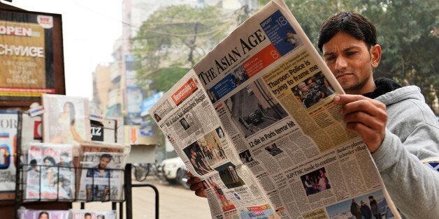 A reader holds up a copy of an English-language Indian newspaper with a front page report on the attack by gunmen on French s