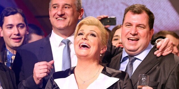 The presidential candidate of the conservative Croatian Democratic Union (HDZ), Kolinda Grabar-Kitarovic (C), celebrates next