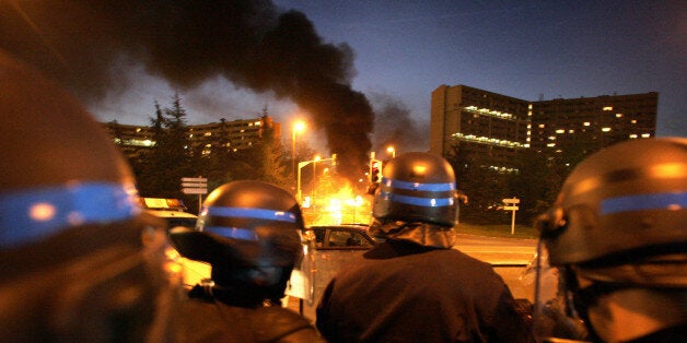 Policemen stand guard as a bus is burning at the entrance of 'Le Mirail', a sensitive neighbourghood of Toulouse, west southe