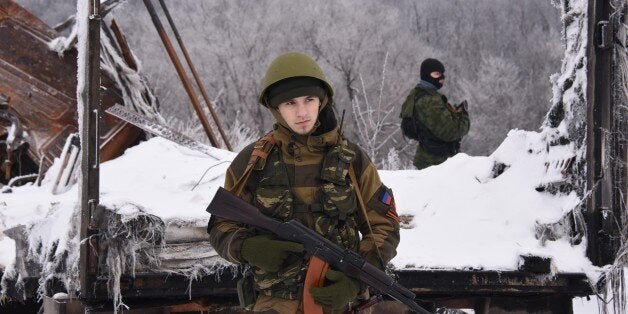 Two pro-Russian rebels guard the road near the airport of Donetsk, with a destroyed bridge in the background, eastern Ukraine, Tuesday, Jan. 6, 2015. Ukrainian soldiers took up duties Tuesday at the Donetsk Airport, scene of some of the fiercest fighting in eastern Ukraine. The 50 soldiers in a convoy of four trucks were provided safe passage to the airport by rebel forces, who gave them gifts in celebration of Orthodox Christmas. (AP Photo/Mstyslav Chernov)