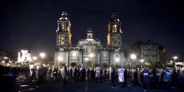 Riot police hold their position outside the National Palace during clashes with protesters over 43 missing students in Mexico City on November 20, 2014. Protesters angry at the presumed massacre of 43 students clashed with police after a massive march demanding President Enrique Pena Nieto's resignation. AFP PHOTO / Yuri CORTEZ (Photo credit should read YURI CORTEZ/AFP/Getty Images)