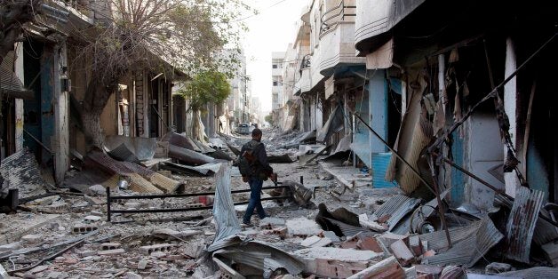 In this Wednesday, Nov. 19, 2014 photo, a Kurdish fighter walks through rubble in Kobani, Syria. In a surprising display of r