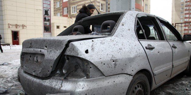 A man stands next to his car destroyed after shelling between Ukrainian army and pro-Russian separatists in the eastern Ukrainian city of Donetsk on January 18, 2015. Ukraine rushed tanks to the front lines in a counter-offensive against pro-Russian rebels fighting for control of Donetsk airport, with heavy shelling shaking the key eastern city. At least six people were killed, including four soldiers, houses were destroyed and electricity was cut for many homes and businesses as explosions repeatedly ripped through parts of the Donetsk region. AFP PHOTO/ ALEKSANDER GAYUK (Photo credit should read SERGEI GAPON/AFP/Getty Images)