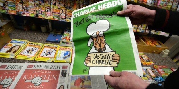 A man holds a copy of French satirical weekly 'Charlie Hebdo' at a newsagent's in Freiburg, southwestern Germany, where two copies of the French satirical weekly 'Charlie Hebdo' were sold on January 17, 2015. The first issue of satirical magazine Charlie Hebdo to be published since a jihadist attack decimated its editorial staff was sold out within minutes at kiosks across Germany, where the sale of only a few copies started on January 17. AFP PHOTO / DPA / PATRICK SEEGER +++ GERMANY OUT (Photo credit should read PATRICK SEEGER/AFP/Getty Images)