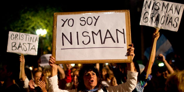 A demonstrator holds a sign that reads in Spanish "I am Nisman" during a protest sparked by the death of special prosecutor Alberto Nisman, outside the government house in Plaza de Mayo in Buenos Aires, Argentina, Monday, Jan. 19, 2015. The other signs read "Enough Cristina," left, and "Thank you Nisman." Nisman, who had been investigating the 1994 bombing of the AMIA Jewish community center in Buenos Aires that killed 85 people and who accused President Cristina Fernandez of shielding Iranian suspects, was found dead with a gunshot to his head in the bathroom of his apartment late Sunday, hours before he was to testify in a Congressional hearing about the case. (AP Photo/Rodrigo Abd)