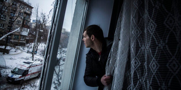 Alexander, 35, looks through a broken window of his flat, hit by Ukrainian Army Artillery, in the Voroshilovsky area, center