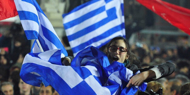 A woman waves a Greek flag during a speech by the leader of Syriza left-wing party Alexis Tsipras outside Athens University Headquarters, Sunday, Jan. 25, 2015. A triumphant Alexis Tsipras told Greeks that his radical left Syriza party's win in Sunday's early general election meant an end to austerity and humiliation and that the country's regular and often fraught debt inspections were a thing of the past. "Today the Greek people have made history. Hope has made history," Tsipras said in his victory speech at a conference hall in central Athens. (AP Photo/Fotis Plegas G.)