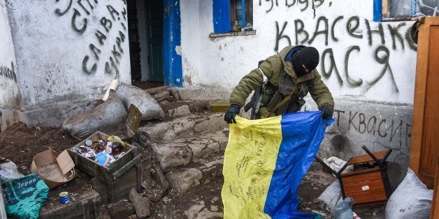 A pro-Russian rebel holds a Ukrainian flag found in a check-point captured by pro-Russian rebels, at the town of Krasniy Part