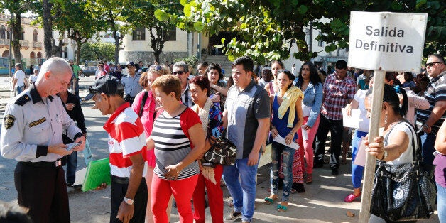 People queue for visas at the U.S. Interests Section in Havana, Cuba, Monday, Dec. 22, 2014. After the surprise announcement of the restoration of diplomatic ties between Cuba and the U.S., many Cubans expressed hope that it will mean greater access to jobs and the comforts taken for granted elsewhere, and lift their struggling economy. The sign on the post reads in Spanish "definite Exit." (AP Photo/Desmond Boylan)