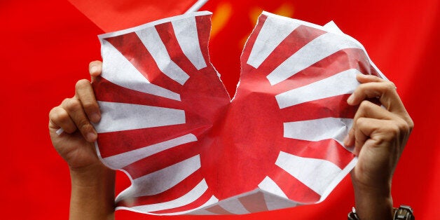 FILE - In this Aug. 16, 2012 file photo, an anti-Japan protester tears Japanese Rising Sun Flag during a rally outside the Japanese Consulate General in Hong Kong as they demand Japanese government to release Chinese activists arrested in Japan after landing on Uotsuri Island, one of the islands of Senkaku in Japanese and Diaoyu in Chinese. Although the Japanese government purchase of Senkaku or Diaoyu, was ostensibly aimed reducing tensions, the move was seen in China as an attempt to solidify Tokyoâs sovereignty over the islets. Outraged Chinese staged violent street protests and attacked Japanese property. (AP Photo/Kin Cheung, File)