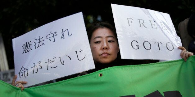 A protester holds placards during a rally outside the Prime Minister's official residence in Tokyo, Tuesday, Jan. 27, 2015. A Japanese envoy in Jordan expressed hope that both a Japanese hostage and a Jordanian pilot held by Islamic militants will return home âwith a smile on their faces,â as criticisms mounted Tuesday over the governmentâs handling of the crisis. The placard at left reads: "Stick with law, life is important." (AP Photo/Eugene Hoshiko)