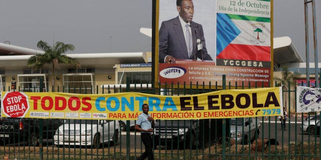 A man walk past sign saying we are all against Ebola at the Malabo International Airport in Malabo, Equatorial Guinea, Saturday, Jan. 17, 2015. (AP Photo/Sunday Alamba)