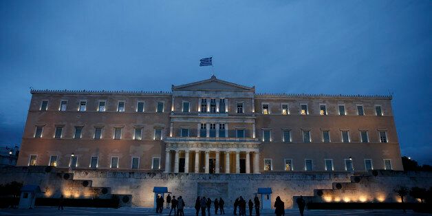 People stand in front of the monument of the unknown soldier in front of the parliament building in Athens, on Friday, Jan. 30, 2015. Greeceâs Parliamentary Budget Office, which makes quarterly recommendations to lawmakers, warned that the country faces default unless a deal with creditors is reached soon. Greece's new government is in open dispute with creditors over the future of the country's bailout program, and is calling for more than half the rescue loans repayments to be cancelled. (AP Photo/Petros Giannakouris)
