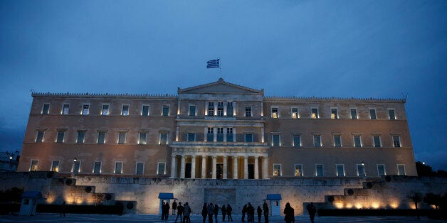 People stand in front of the monument of the unknown soldier in front of the parliament building in Athens, on Friday, Jan. 3