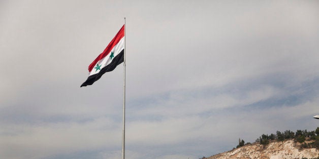 In this Monday, Oct. 27, 2014 photo, a Syrian flag flies over the capital, Damascus, Syria. Syrians are adjusting to life in
