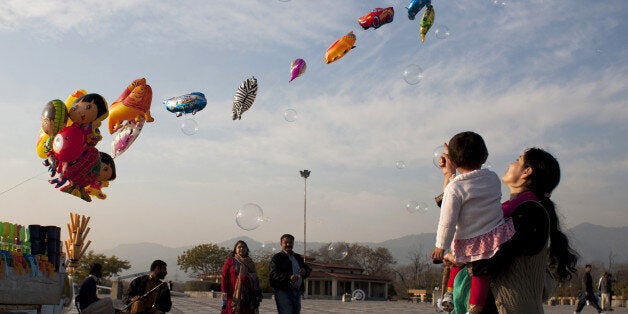 A Pakistani woman shows her daughter bubbles released by a vendor in Lake View park in Islamabad, Pakistan, Saturday, Jan. 24