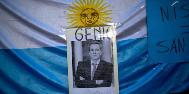 A portrait of late prosecutor Alberto Nisman is seen pasted on an Argentine flag with a title that reads in Spanish "Genius," outside a funeral home during his wake in Buenos Aires, Argentina, Thursday, Jan. 29, 2015. Nisman was scheduled to appear before congress the day after he was found dead in his apartment on Jan. 18, to detail his allegations that President Cristina Fernandez had conspired to protect some of the Iranian suspects in the 1994 bombing of a Jewish center. The man who gave Nisman the gun that killed him said Wednesday that Nisman feared for the safety of his daughters and didn't trust the policemen protecting him. (AP Photo/Rodrigo Abd)
