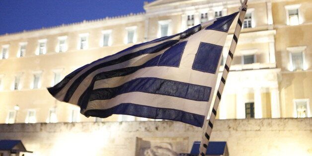 SYNTAGMA SQUARE, ATHENS, ATTICA, GREECE - 2015/02/05: A protester waves a Greek flag outside the Greek Parliament. Thousands of Greeks assembled at Syntagma Square, to protest against the fiscal extortion by the Troika,Â who wants Greece to follow their instruction in return for providing needed money to the Greek banks. (Photo by Michael Debets/Pacific Press/LightRocket via Getty Images)
