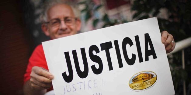 BUENOS AIRES, ARGENTINA - JANUARY 21: A man holds a placard that reads 'Justice' outside the headquarters of AMIA (Argentine Israelite Mutual Association) during a demonstration to demand justice in the death of Argentine prosecutor Alberto Nisman in Buenos Aires, Argentina, on January 21, 2015. Alberto Nisman who had accused President Cristina Fernandez de Kirchner of covering up Irans alleged involvement in a deadly Jewish center bombing in 1994, was found dead in his Buenos Aires apartment early Monday with a gunshot wound to his head. (Photo by Rodrigo Ruiz Ciancia/Anadolu Agency/Getty Images)