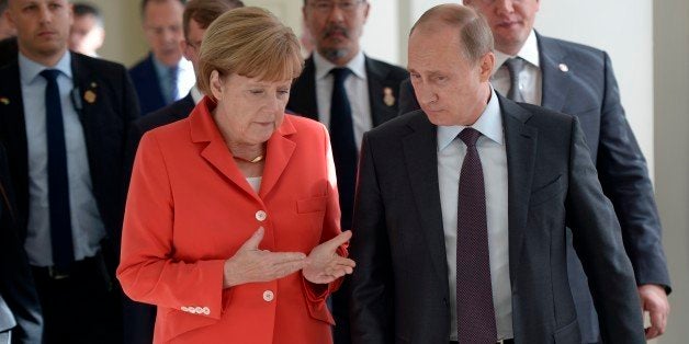 In this photo taken on Sunday, July 13, 2014 Russian President Vladimir Putin, right, and German Chancellor Angela Merkel speak to each other before the World Cup final between Germany and Argentina in Rio de Janeiro, Brazil. (AP Photo/RIA-Novosti, Alexei Nikolsky, Presidential Press Service)