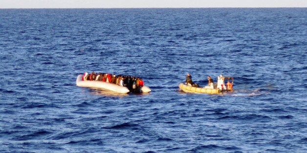 In this photo taken on Thursday, Dec. 4, 2014 provided by the Italian Navy, a rescue crew on a dinghy, right, approaches migrants on a boat some 40 miles (65 kilometers) from the Libyan capital, Tripoli. Rescue crews discovered 16 bodies in a migrant boat off Libya, the first reported deaths since the European Union took over Mediterranean rescue operations, the Italian navy said Friday. The EU operation, launched last month after Italy phased out its more robust rescue program, foresees patrols 30 miles (50 kilometers) from the Italian coast. (AP Photo/Italian Navy)