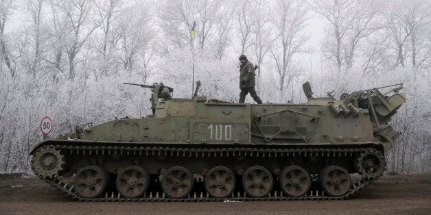Ukrainian government soldier walks atop of his armored vehicle on the road between the towns of Dabeltseve and Artemivsk, Ukr