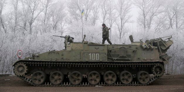 Ukrainian government soldier walks atop of his armored vehicle on the road between the towns of Dabeltseve and Artemivsk, Ukraine, Sunday, Feb. 15, 2015. International attention will be focused in the coming days on the strategic railway hub of Debaltseve, where Ukrainian government forces have for weeks been fending off severe onslaughts from pro-Russian separatists. A cease-fire was declared in eastern Ukraine, kindling slender hopes of a reprieve from a conflict that has claimed more than 5,300 lives. (AP Photo/Petr David Josek)