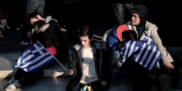 A boy holds a Greek flag during an anti-austerity, pro-government demonstration in front of the Greek Parliament in Athens on