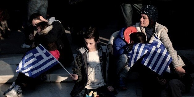 A boy holds a Greek flag during an anti-austerity, pro-government demonstration in front of the Greek Parliament in Athens on February 15, 2015. Prime Minister Alexis Tsipras said he was 'confident' about progress in renegotiating Greece's debt at a crucial eurozone meeting on February 16, in an interview with German media. AFP PHOTO / ANGELOS TZORTZINIS (Photo credit should read ANGELOS TZORTZINIS/AFP/Getty Images)