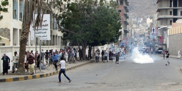 ADEN, YEMEN - FEBRUARY 15: Security forces intervene with tear gas as pro-separatist Yemenis stage a protest in Kraytar region of Aden, Yemen on February 15, 2015. Protestors hold flags, set tires fire during demonstration. (Photo by Stringer/Anadolu Agency/Getty Images)