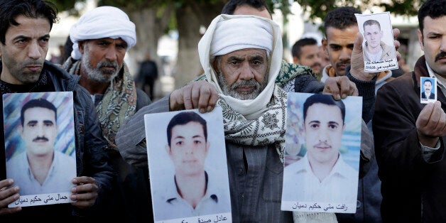 Coptic Christian men whose relatives were abducted in Libya hold their photos in front of the foreign ministry in Cairo, Egypt, Monday, Jan. 19, 2015. Masked gunmen kidnapped 21 Coptic Christians last month in the central Libyan city of Sirte in a new wave of assaults against Egypt's Christians working in the war-torn North African nation plagued with Islamic extremists. A Libyan affiliate of the Islamic State has claimed the abduction of 21 Coptic Christians and released pictures of the captives. The claim and photos were posted last week on jihadi forums used by Islamic State supporters. (AP Photo/Hassan Ammar)