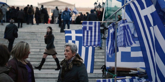 Women talk next to Greek flags for sale in Syntagma square, Monday, Feb. 16, 2015. Greece and its creditors in the 19-country