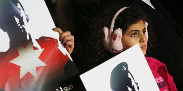 AMMAN, JORDAN- FEBRUARY 08: A Child holds a poster as Jordanian journalists hold a candlelight vigil expressing their solidarity for a pilot murdered by the Islamic State (ISIS) group, on February 8, 2015 in Amman, Jordan. Jordan has launched dozens of airstrikes against ISIS since the militant group released a video of them burning to death Jordanian pilot Lt Moaz al-Kasaesbeh. (Photo by Jordan Pix/Getty Images)