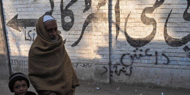 Pakistani pedestrians walk past wall graffiti (bottom) which reads Daesh, the arabic acronym for Islamic State (IS), in Peshawar on November 22, 2014. The Islamic State organisation is starting to attract the attention of radicals in Pakistan and Afghanistan, long a cradle for Islamist militancy, unnerving authorities who fear a potential violent contagion. AFP PHOTO/A MAJEED (Photo credit should read A Majeed/AFP/Getty Images)