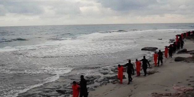 FILE - In this file image made from a video released Sunday, Feb. 15, 2015 by militants in Libya claiming loyalty to the Islamic State group purportedly shows Egyptian Coptic Christians in orange jumpsuits being led along a beach, each accompanied by a masked militant. Libya, virtually a failed state the past years, has provided a perfect opportunity for the Islamic State group to expand from its heartland of Syria and Iraq to establish a strategic stronghold close to European shores. (AP Photo, File)