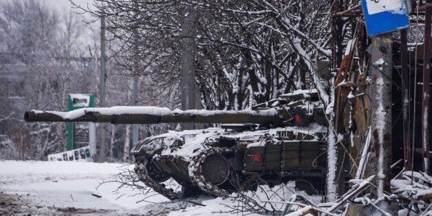 A pro-Russian rebels' tank stands behind a destroyed bus stop near Donetsk airport, Eastern Ukraine, Tuesday, Jan. 6, 2015. U
