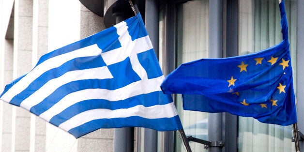 The Greek, left, and EU flag flap in the wind outside the Greek embassy in Brussels on Friday, Feb. 20, 2015. Eurozone finance ministers meet for a crucial day of talks to see whether a Greek debt relief proposal is acceptable to Germany and other nations using the common currency. (AP Photo/Virginia Mayo)