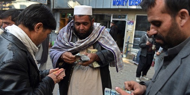 TO GO WITH Afghanistan-unrest-economy-mining-NATO,FOCUS by Guillaume LAVALLÃEIn this photograph taken on December 29, 2014, Afghan money changers count Afghani bank notes at the currency exchange Sarayee Shahzada market in Kabul. The Taliban insurgency may still be raging but the poor state of the economy could pose a bigger threat to Afghanistan's long-term viability, and huge mineral reserves are unlikely to offer a quick fix. In Kabul's Sarayee Shahzada market, moneychangers wave thick bundles of Afghanis, dollars, rupees and dirhams, but the customers are not packing the alleyways like they used to and business is well down on two years ago. AFP PHOTO / Wakil Kohsar (Photo credit should read WAKIL KOHSAR/AFP/Getty Images)