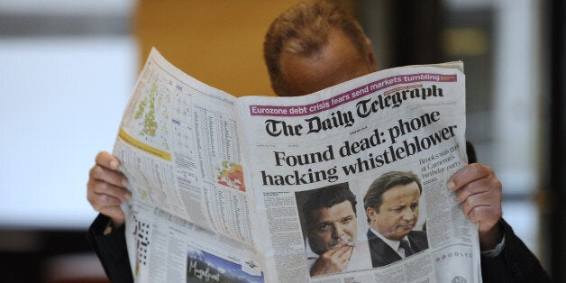 A person reads on July 19, 2011, in Paris, the British daily newspaper, The Daily Telegraph of which front page is on the spiralling phone-hacking scandal. Australian-born and US head of the global News Corporation empire, Rupert Murdoch, his son James and former News International chief executive Rebekah Brooks faced questions on July 19, from British lawmakers over the News of the World phone-hacking scandal which has shaken the British establishment and placed Prime Minister David Cameron under pressure. A whistleblower in this scandal, former News of the World reporter Sean Hoare, was found dead at his home on July 18, but there appeared to be no suspicious circumstances, police said. AFP PHOTO MIGUEL MEDINA (Photo credit should read MIGUEL MEDINA/AFP/Getty Images)