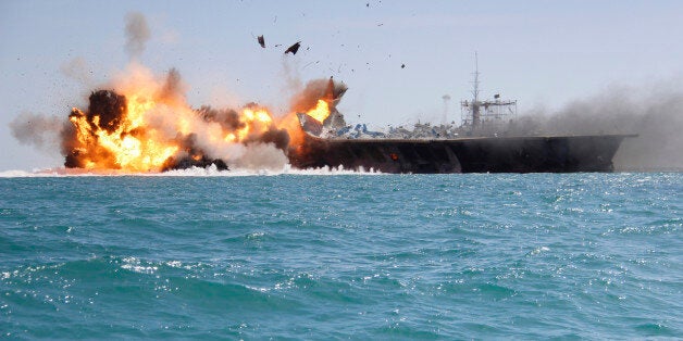 In this picture released by the Iranian Tasnim news agency on Wednesday, Feb. 25, 2015, a replica of a U.S. aircraft carrier is exploded by the Revolutionary Guard's speedboats during large-scale naval drills near the entrance of the Persian Gulf, Iran. The drill, named Great Prophet 9, was the first to involve a replica of a U.S. carrier. Cmdr. Kevin Stephens, the spokesman for the U.S. Navy's 5th Fleet in Bahrain, said they were monitoring the drills, but downplayed the simulated attack on the carrier, saying the U.S. military was "not concerned about this exercise."(AP Photo/Tasnim News)