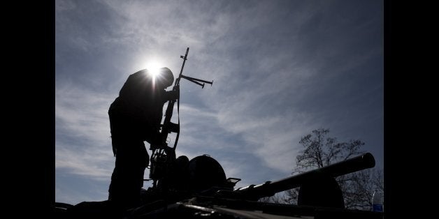 A Ukrainian soldier stands atop a military vehicle near Artemivsk, eastern Ukraine, Monday, Feb. 23, 2015. Ukraine delayed a promised pullback of heavy weapons from the front line Monday in eastern Ukraine, blaming continuing attacks from separatist rebels. (AP Photo/Evgeniy Maloletka)