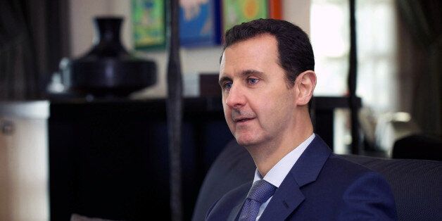 In this photo released by the Syrian official news agency SANA, Syrian President Bashar Assad, right, speaks during an interview with a U.S. magazine, in Damascus, Syria, Monday, Jan. 26, 2015. Assad has dismissed negotiations with "puppets" in an interview with a U.S. magazine ahead of talks set to begin in Moscow. (AP Photo/SANA)