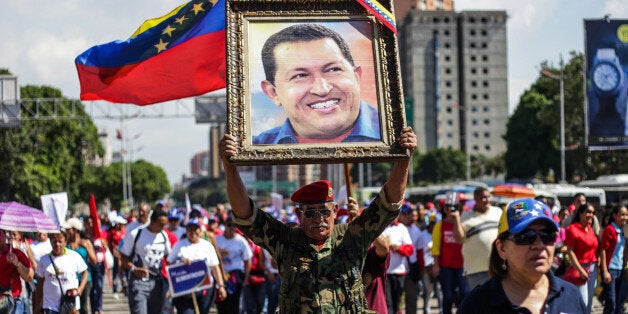 CARACAS, VENEZUELA - DECEMBER 15 : A man holds a portrait of late Venezuelan leader Hugo Chavez as Venezuelans gather on the streets of Caracas to commemorate the 15 years of the adoption of the new Venezuelan Constitution on December 15, 2014. (Photo by Cristian Hernandez/Anadolu Agency/Getty Images)