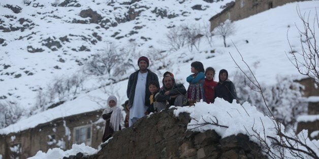 Afghan villagers look on in a village close to an avalanche site in Panjshir province north of Kabul, Afghanistan, Wednesday, Feb. 25, 2015. Avalanches caused by a heavy winter snow killed at least 124 people in northeastern Afghanistan, an emergency official said Wednesday, as rescuers clawed through debris with their hands to save those buried beneath. (AP Photo/Massoud Hossaini)