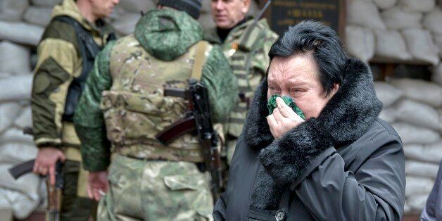 A woman reacts as she walks past pro-Russian rebels guarding the Zasyadko mine in Donetsk, Ukraine Wednesday March 4, 2015. An explosion at the Zasyadko coal mine in war-torn eastern Ukraine killed 32 workers on Wednesday, the speaker of Ukraine's parliament said. Rebels who control the area, however, confirmed only one death. (AP Photo/Vadim Ghirda)