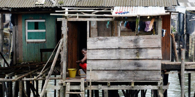 BUENAVENTURA, COLOMBIA - JANUARY 13, 2015: A woman busy with her house duties looks at the camera from the opposite neighborhood of Puente Nayero on January 13, 2015 in Buenaventura, Colombia. Puente Nayero slum is an arms and violence free humanitarian space on a dirt track road near the seafront with no criminals or paramilitary actors, created by one of the community leaders and help of Inter-Ecclesiastic Commission of Justice and Peace, a Colombian human rights NGO, to help facilitate the establishment and accompaniment of the Space. (Photo by Kaveh Kazemi/Getty Images)