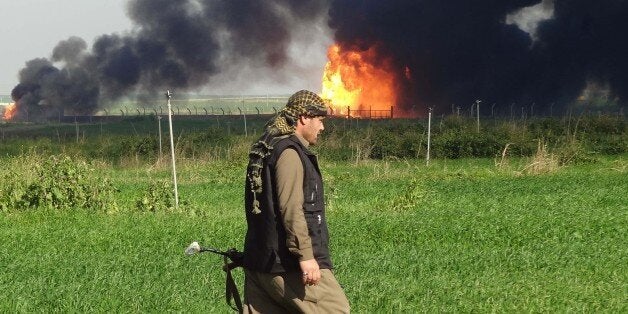 A member of the Kurdish Peshmerga forces walks at the Khubbaz oil field, some 25 km west of the northern city of Kirkuk, as s
