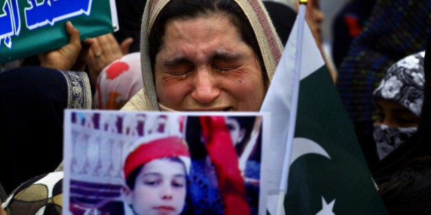 A mother weeps as she carries a picture of her slain son during a tribute to students who were killed in an attack on a school last year by Taliban gunmen, in Peshawar, Pakistan, Saturday, Feb. 7, 2015. Pakistani Taliban militants attacked an army-run school in the northwestern city of Peshawar on Dec. 16, 2014, killing 150 people, mostly children. (AP Photo/Mohammad Sajjad)