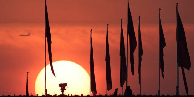 Chinese military personnel watch over Tiananmen Square from a rooftop across from the Great Hall of the People, as the sun ri